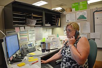 Maria Gregory, a specialist with Duke's Human Resources Information Center, talks with a caller about benefits-related questions. Along with her coworkers, Gregory handles thousands of cases each month. Photo by Bryan Roth.