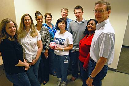 Members of the Internal Audits team with the piggy bank they fill each Friday that they wear jeans to work. This quarter they are raising money for Genesis Home, one of the many local programs supported by the Doing Good in the Neighborhood employee givi