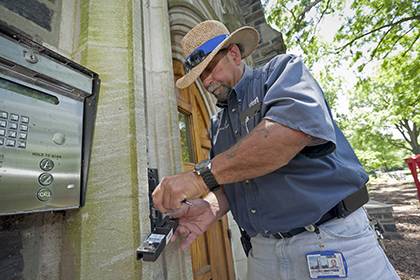 Thomas Falcon, an IT specialist for the DukeCard Office, works on the electronic access system at a building entry. Photo by Duke University Photography.