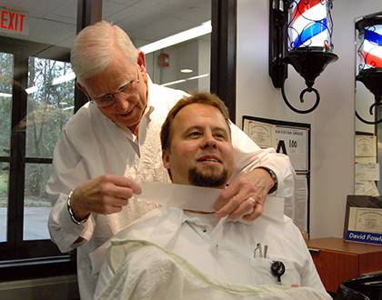 Duke barber Dave Fowler preps Brian Backus, supervisor of sign and graphics services for Duke Engineering and Operasions, for a recent haircut. Fowler has worked at the Duke Barbershop for more than 50 years. Photo by Bryan Roth.