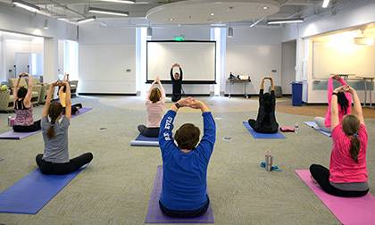 Duke employees in Gross Hall strike a yoga pose during a lunchtime fitness session organized by LIVE FOR LIFE, Duke's employee wellness program. Photo by April Dudash