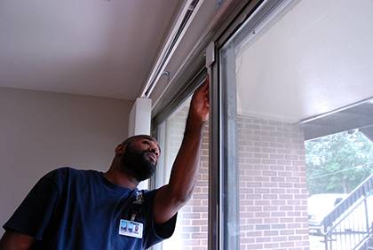 Devon Jenkins, a senior apartment operations maintenance mechanic on Central Campus, inspects a new lock installed on sliding glass doors in Central Campus apartments. New locks have been added to front doors as well. Photo by Bryan Roth.