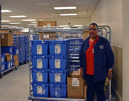 Denise Simpson, customer service representative with Duke Hospital Material Management, poses by a cart with medical supplies, which she delivers to doctors and nurses throughout the hospital. Photo by Alexandria Glenn.