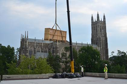 Workers watch as a large box of solar panels is lifted onto the roof of the Bryan Center. The panels are expected to be installed in October and will provide some of the hot water used in the building. (Photo courtesy of Sergey Furer)