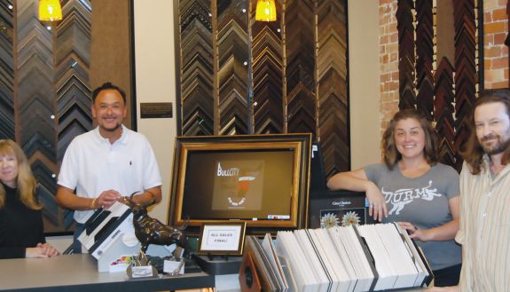Left to right, Bull City Art & Frame staff Michelle Draughon, Lewis Bowles, Tiffany Bowles, and Will Rote stand ready to help frame cherished items. Photo by Jack Frederick.