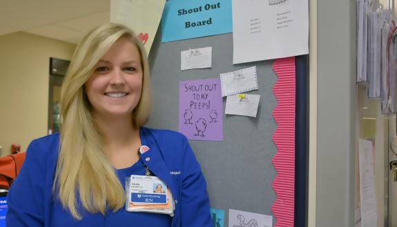Clinical nurse Molly Frazier stands in front of the staff shout-out board in the Duke Raleigh Hospital Emergency Department.