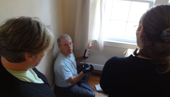 A volunteer with Clean Energy Durham shows a group of Duram residents how to caulk around an air register during a Do-It-Yourself workshop last spring. Durham's Home Energy Retrofit Program offer similar improvements which can help save money. Photo cour