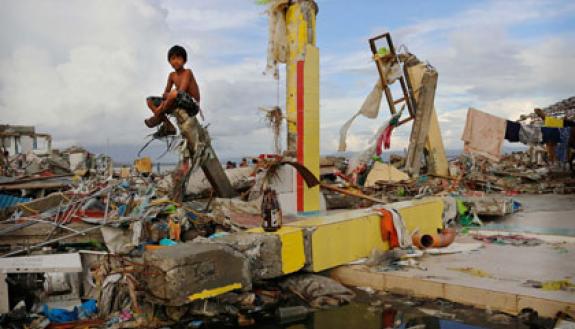 A young boy sits on the ruins in the aftermath of Typhoon Haiyan in Leyte, Philippiines.  Photo: Kevin Frayer/Getty Images
