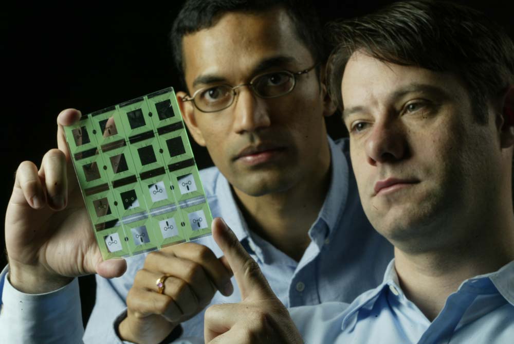 Michael Pollack, right, and Vamsee Pamula examine one of their microfluid chips.