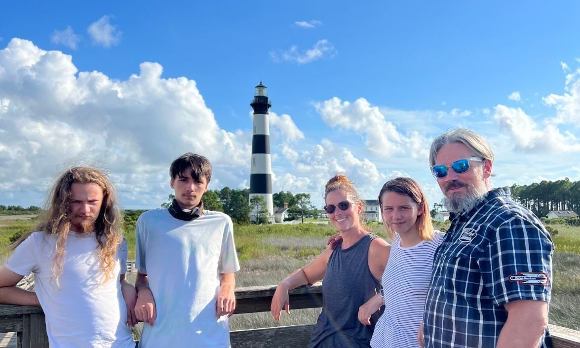 Family standing in front of a lighthouse smiling