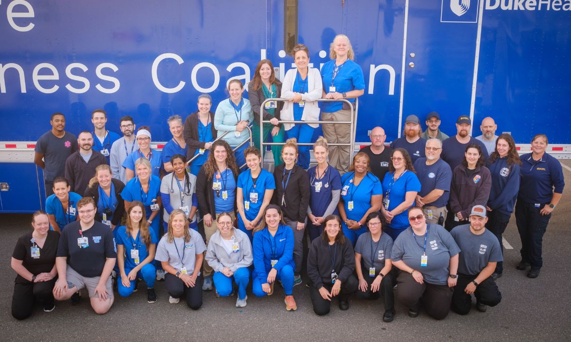 Group of volunteers sitting in front of the Mobile Health Unit