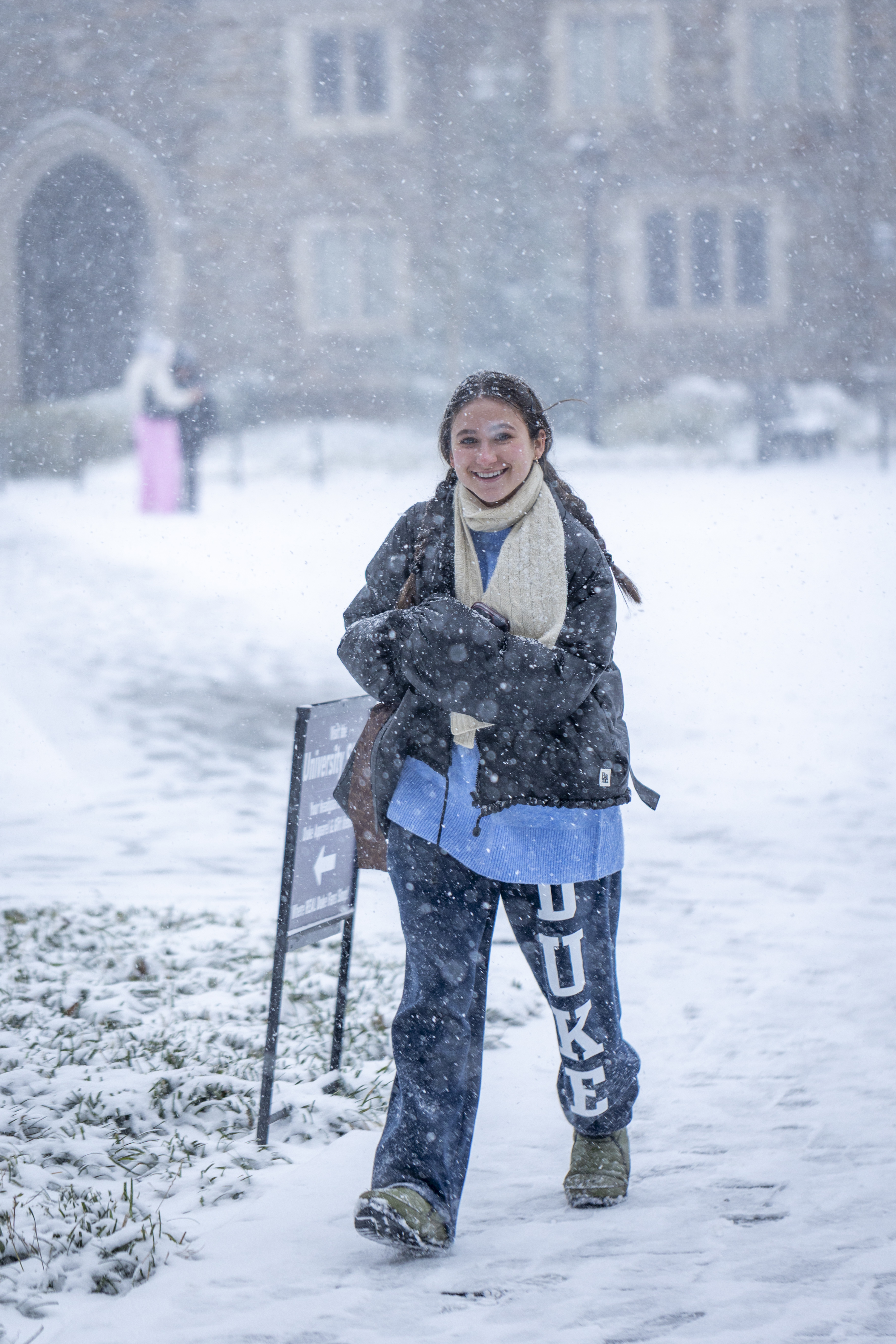 Female student with big smile wearing Duke sweats moves through some heavy snow.