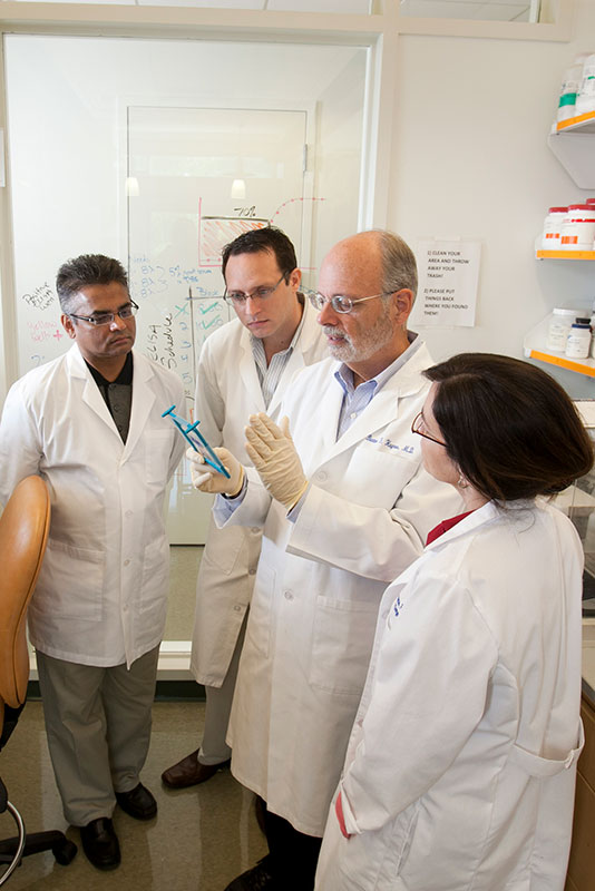 Bart Haynes holding medical equipment talking to a group in lab coats