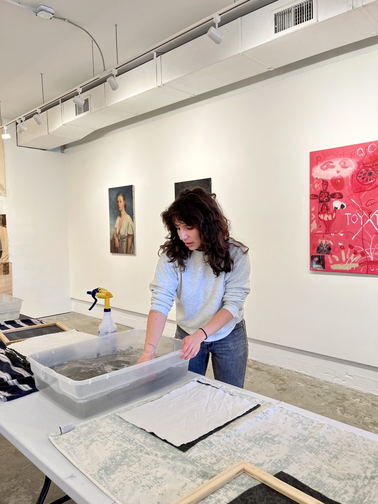 A woman stands at a plastic basin at a paper-making workshop