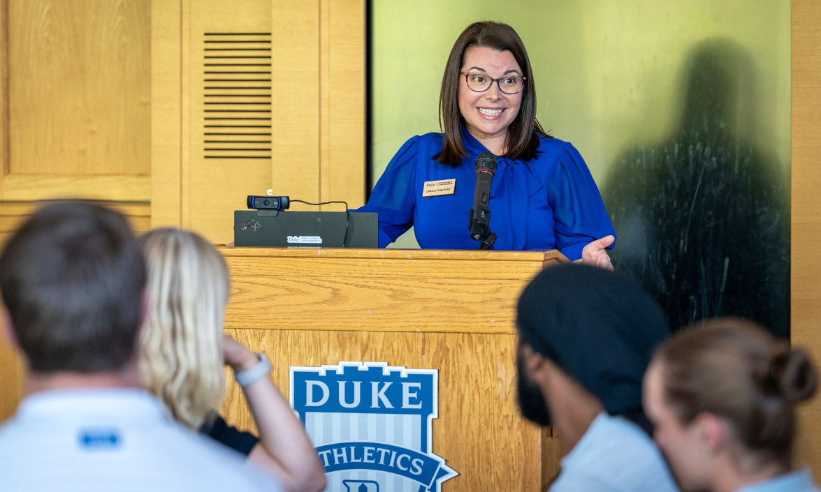 A woman standing at a podium is speaking to an audience.
