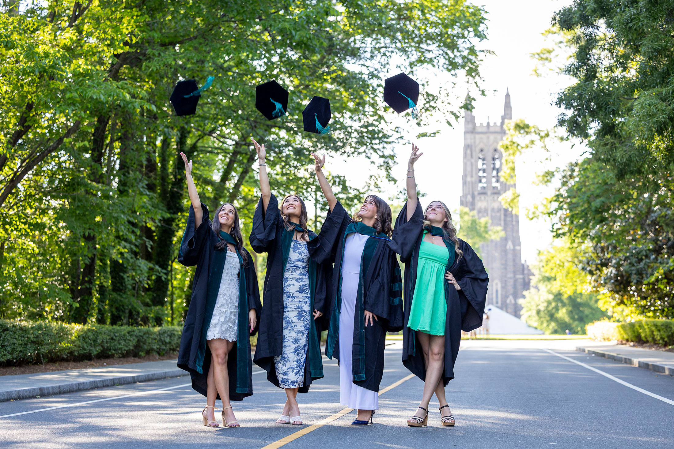 four students tossing caps on Campus Drive