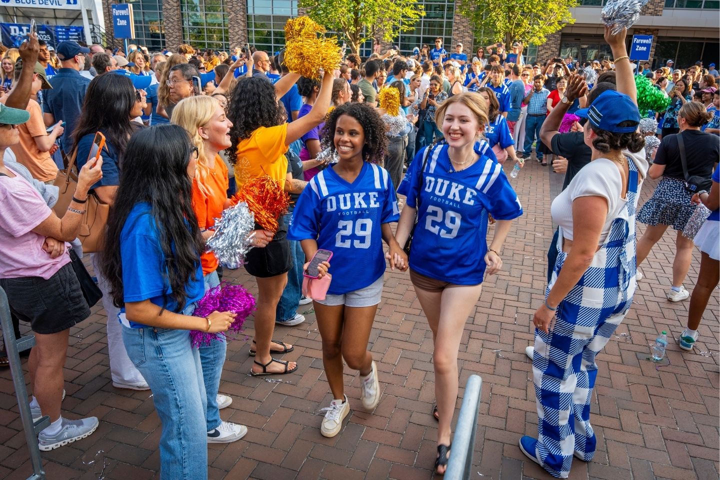 Two student in Duke shirts being cheered on as the go into Cameron Indoor Stadium