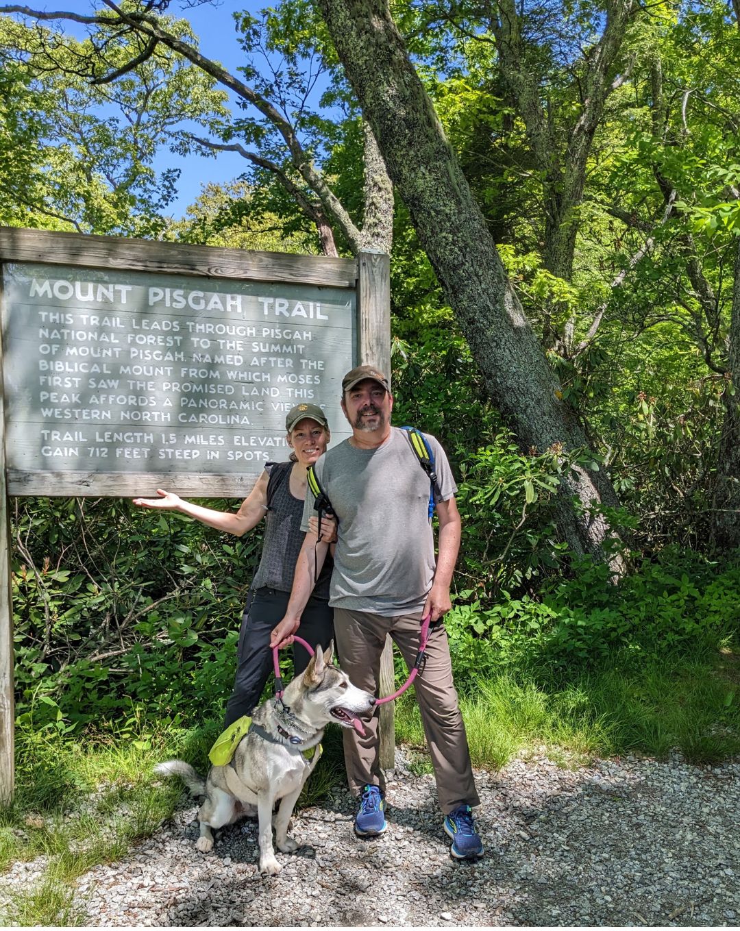 A woman, a man and a dog stand next to a sign that reads Mount Pisgah Trail