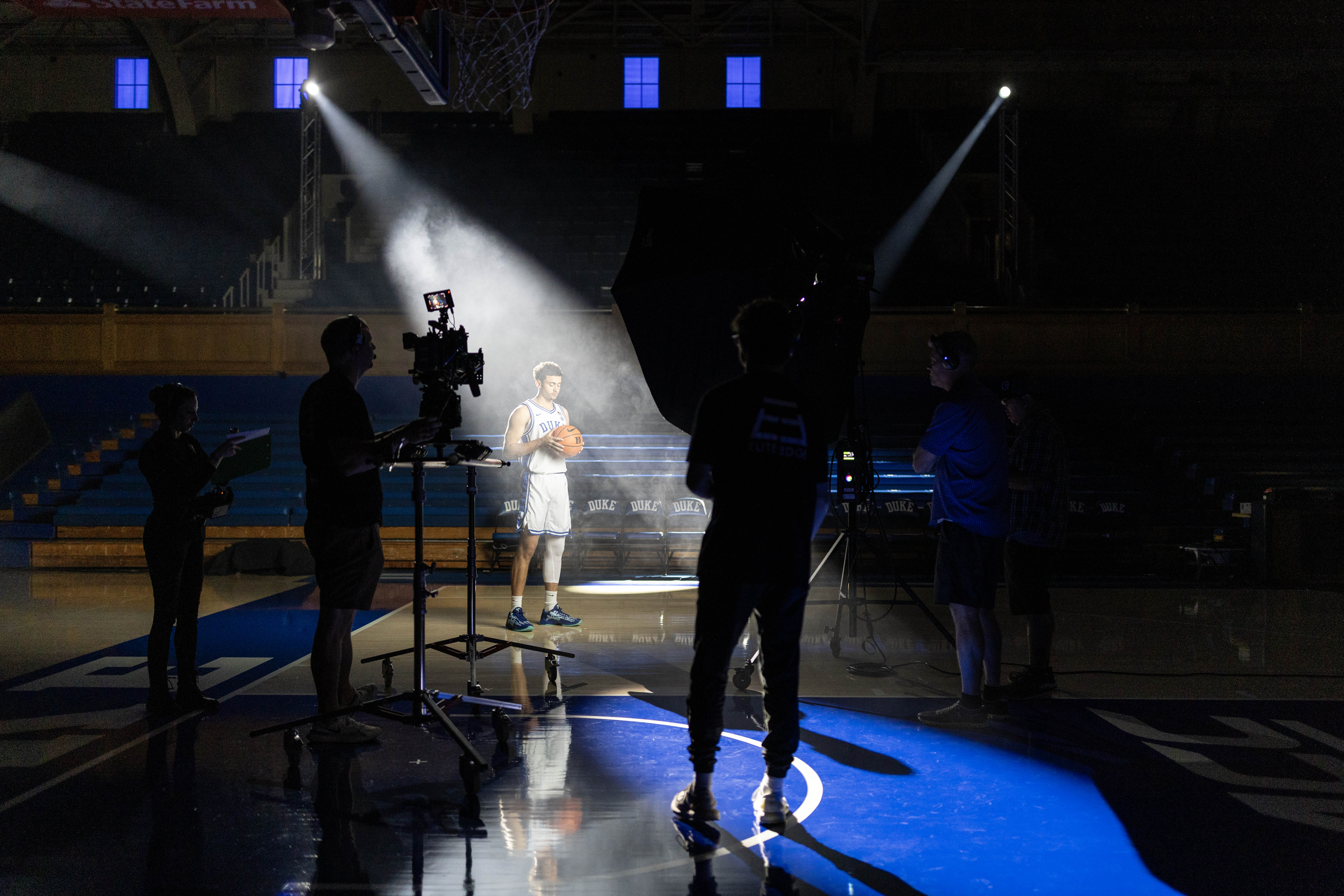 a Duke men's basketball player is illuminated by a spotlight for a photo shoot
