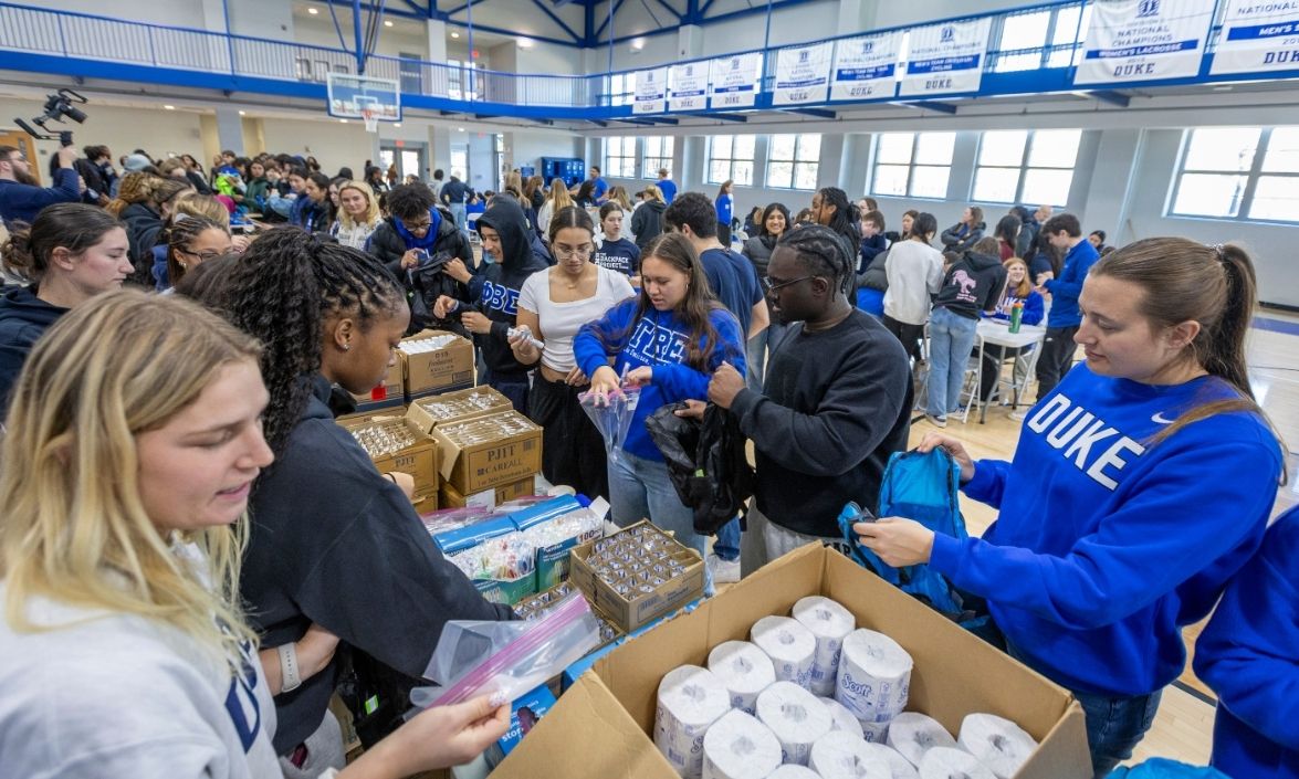 Big crowd of people assembling backpacks