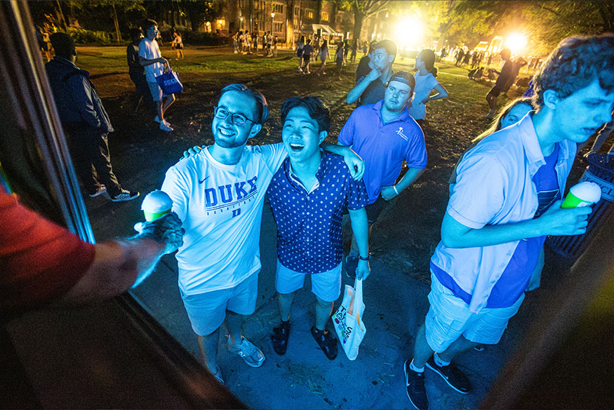 Students lit up by a blue light get snocones from a food truck