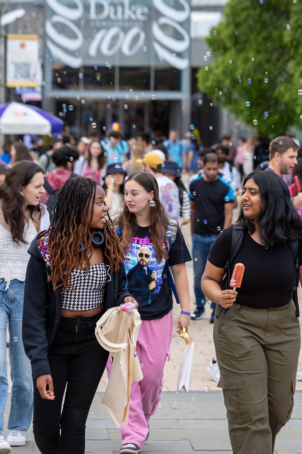 student eat locopops while walking through soap bubbles at the plaza
