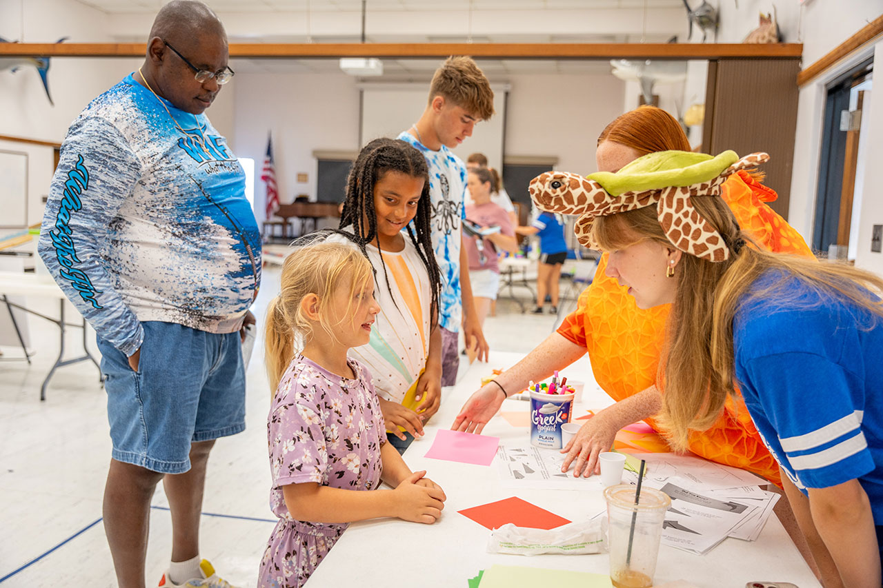 Kids talk to volunteers at a crafts table at the event