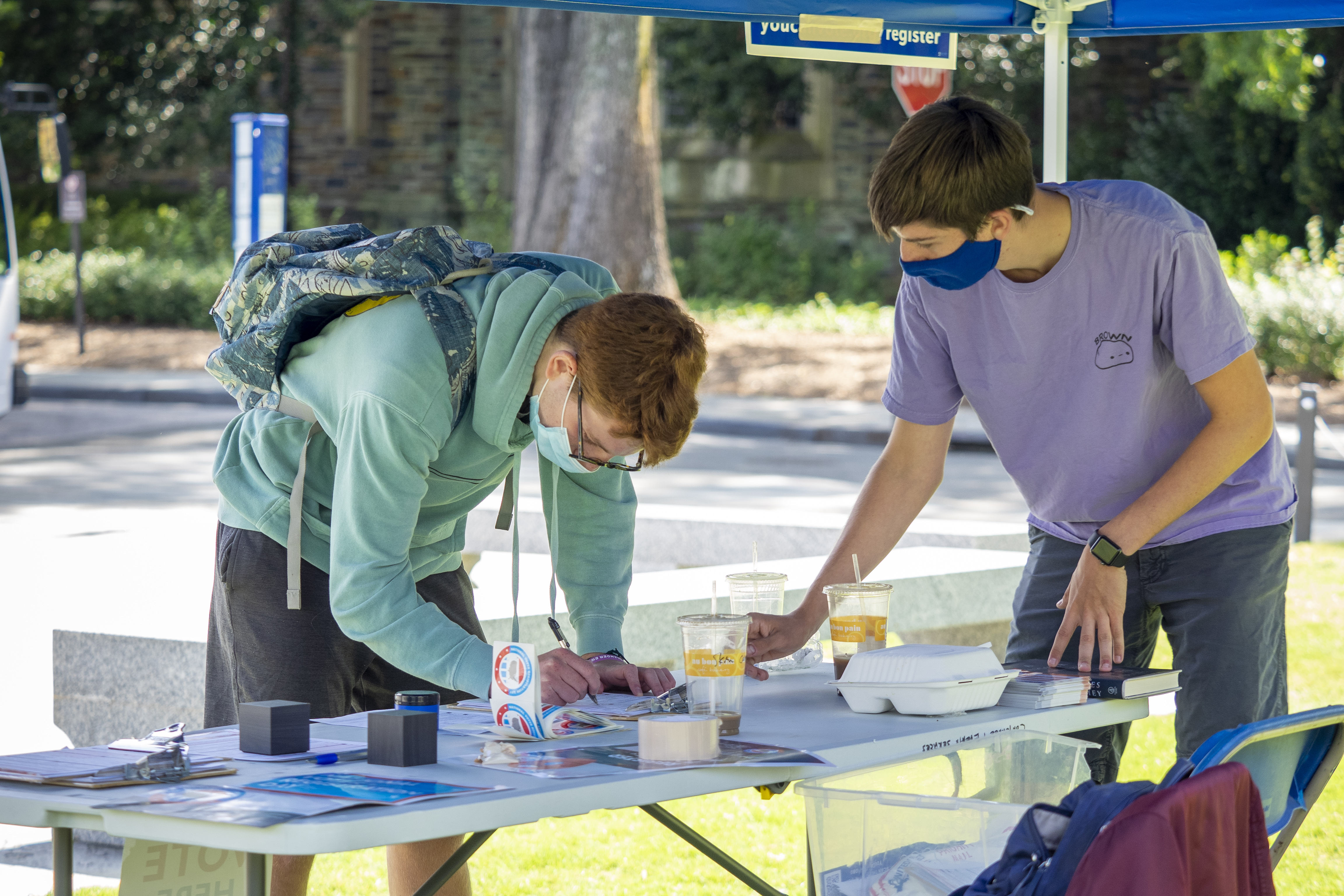 Jonah Perrin helps a student register to vote during the pandemic at a Duke Votes table.