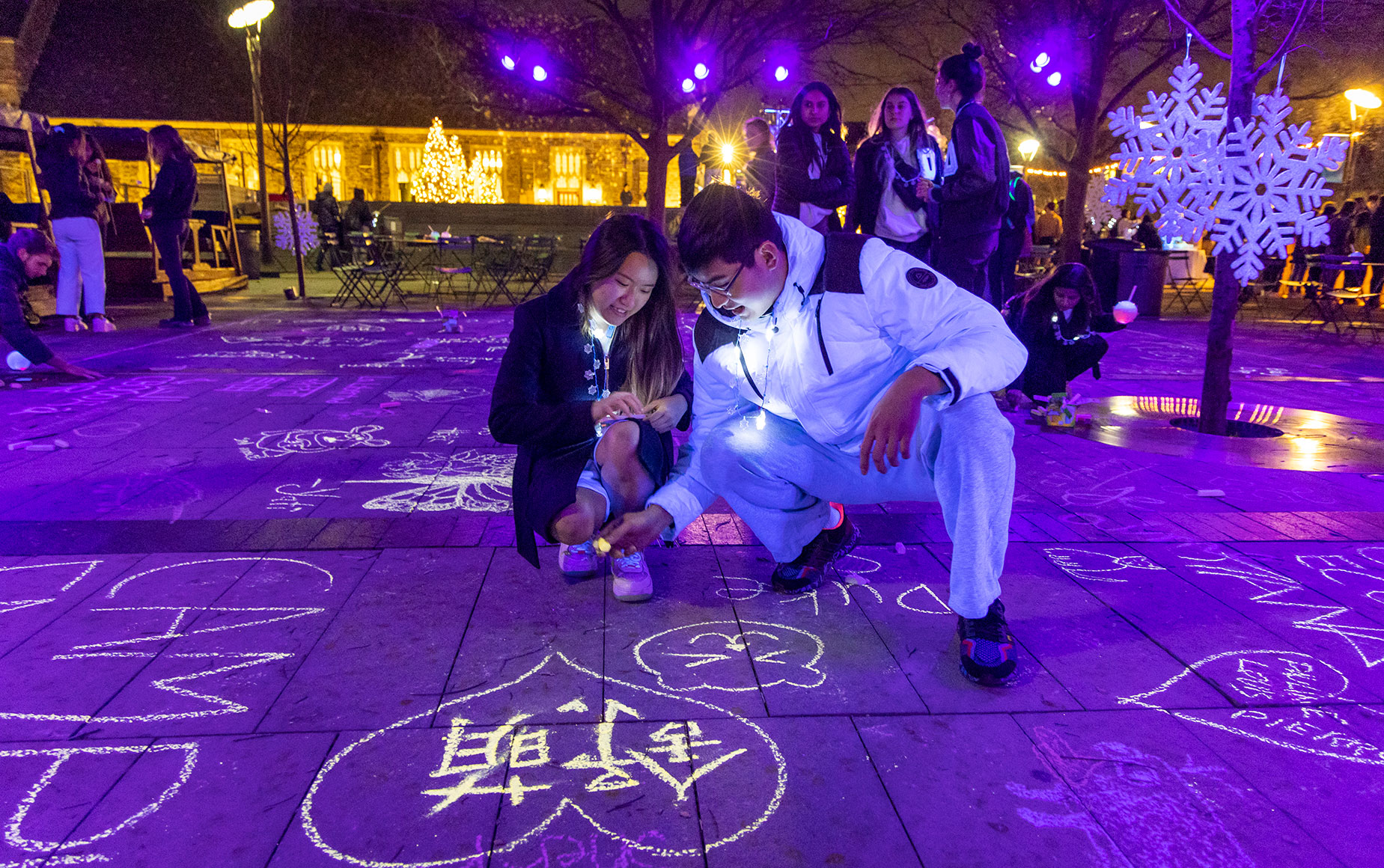 Students use glow chalk to write messages on the Plaza floor. Photo by Jared Lazarus