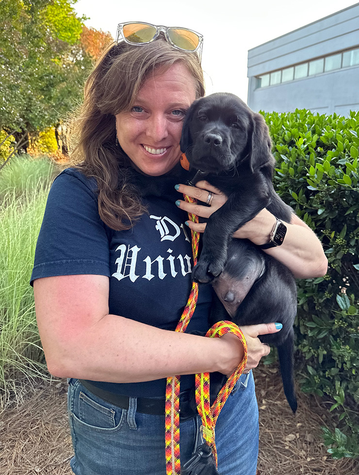 A woman holds a black puppy