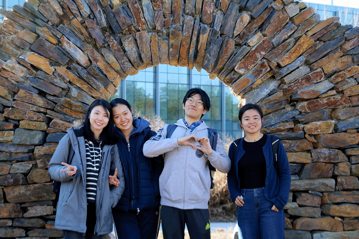 Members of the first cohort of Duke Kunshan IMEP students take a picture under the stone arch outside of the Nicholas School.