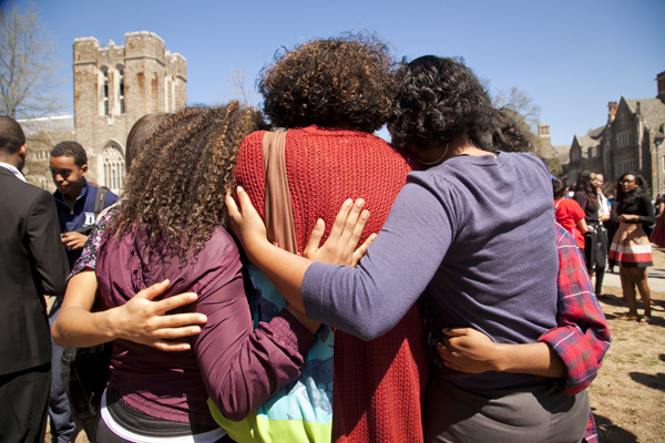 Students embrace in a gathering at the West Campus bus stop.