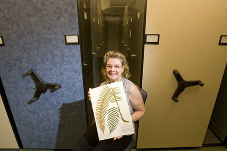 Sherri Herndon poses with one of the flattened and preserved plant species in the Duke Herbarium. 