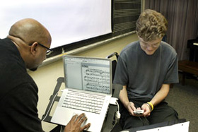 University Photography Professor Anthony Kelley pulls up the sheet music for a Bach chorale on his computer, as junior Geoff Lorenz plays the song from his iPod.