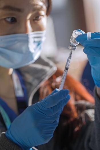 Clinical Pharmacist Wennie Huang measures a dose of the vaccine.