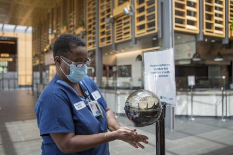 Housekeeper Beverly Jordan uses the hand sanitizer at the entrance to the Brodhead Center, where visitors are encouraged to wash their hands as part of Duke University’s response to the COVID-19 pandemic. 