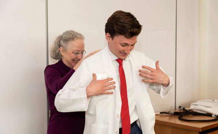 Andy Vogt from Senate Committee on Health, Education, Labor and Pensions tries on his white medical coat. Assisting him is Dr. Caroline Haynes, associate dean for medical education at the School of Medicine. Photo by Les Todd