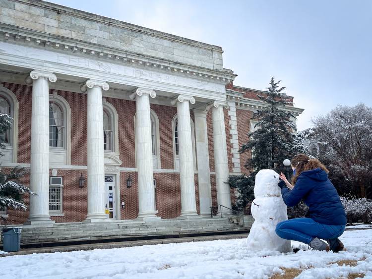 Rhiannon Eplett, a freshman studying biology, builds a snowman in front of Lily Library.