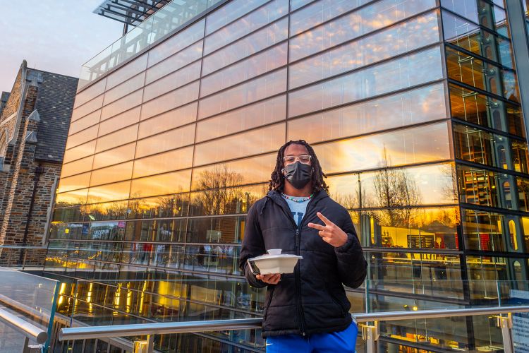 student walks out grab and go meal in front of the Brodhead Center