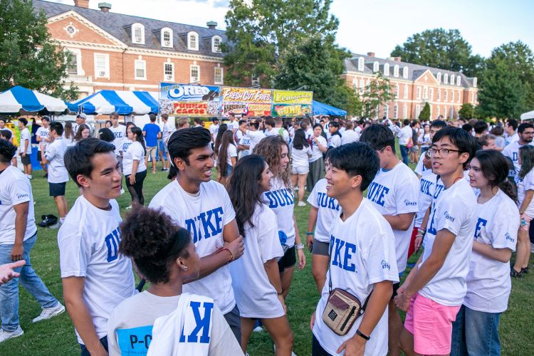 All dressed in a white Duke t-Shirt, Members of the Class of 2026 talk together prior to the class photo.