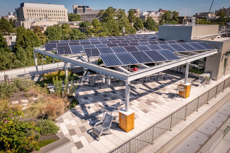 A sutudent sites under the solar panels that shade the roof-top garden at the Nicholas School for the Environment