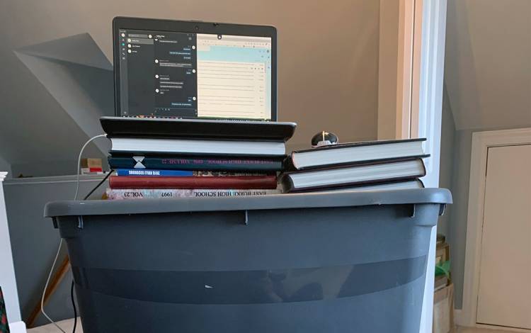 Andrea Martin used some yearbooks and storage bins to create a smart, improvised standing desk. Photo courtesy of Andrea Martin. A computer on storage bins.