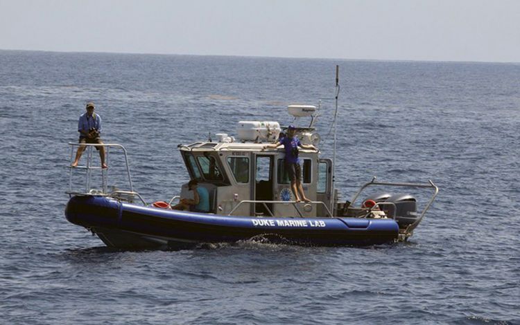 Andy Read, left, sits on the front of The Barber, a 30-foot research boat for the Duke Marine Lab. Photo courtesy of Andy Read.