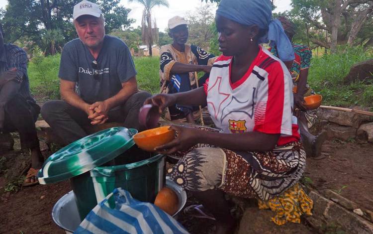 Charles Piot, left, dines with villagers in northern Togo. Photo courtesy of Charles Piot.