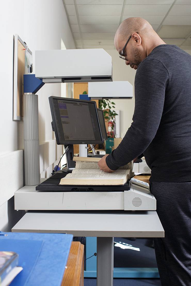 Library Associate Earl Alston scans a portion of a book. Photo by Alex Boerner.