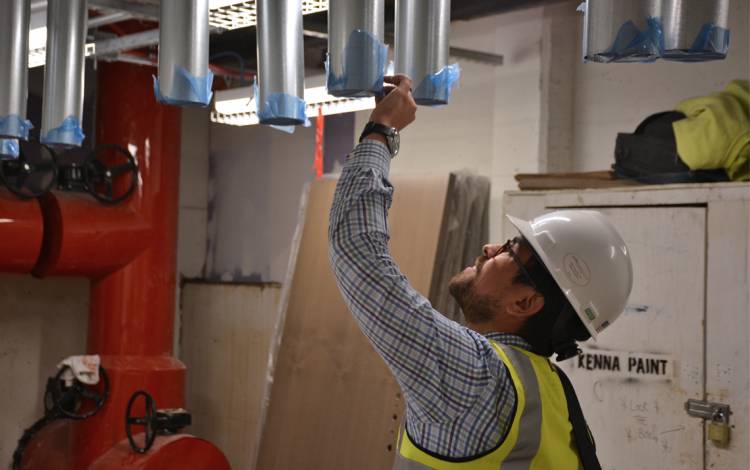 Hector M. Hernandez, Facilities Management Department’s project manager for the Hollows, inspects dryer ducts in the first-floor laundry room of Hollows A this summer. 