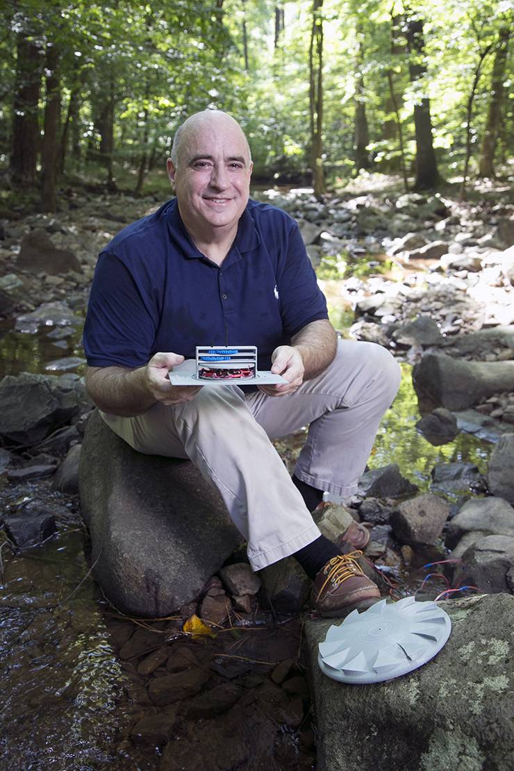 Chris Hubbard holds a prototype for the Hydro Disc, which is designed to create electric current from the flow of a creek or stream.