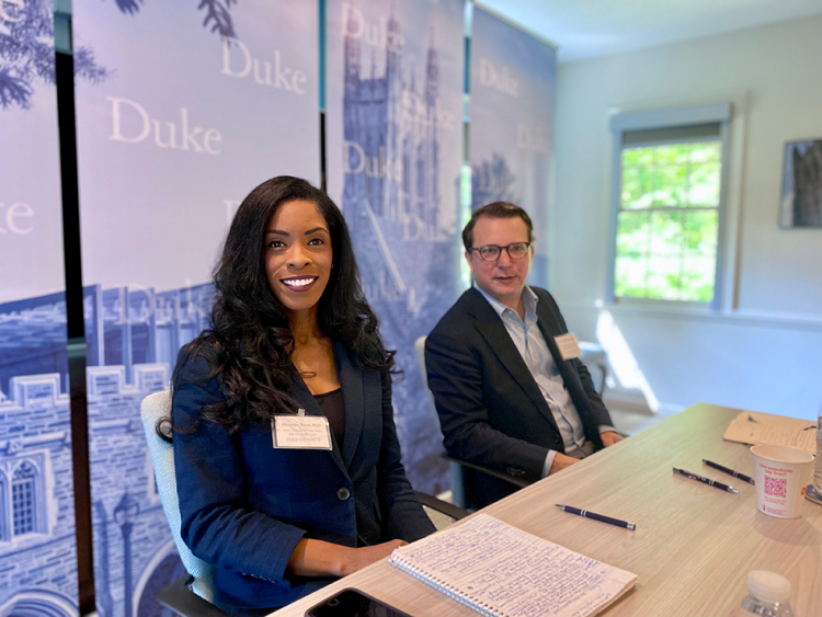 Two individuals sitting in front of banners with Duke logos