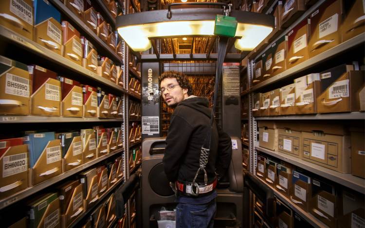Library Assistant Johnny Shanahan guides a lift high in the Library Service Center's stacks. Photo by Alex Boerner.