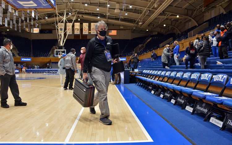Mark Kitchens carries the case containing the scoreboard controls off the floor. Photo by Stephen Schramm.